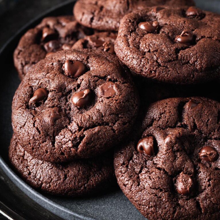 Close-up of double-chocolate peanut butter cookies arranged on a dark plate, highlighting their soft texture and glossy chocolate chips.