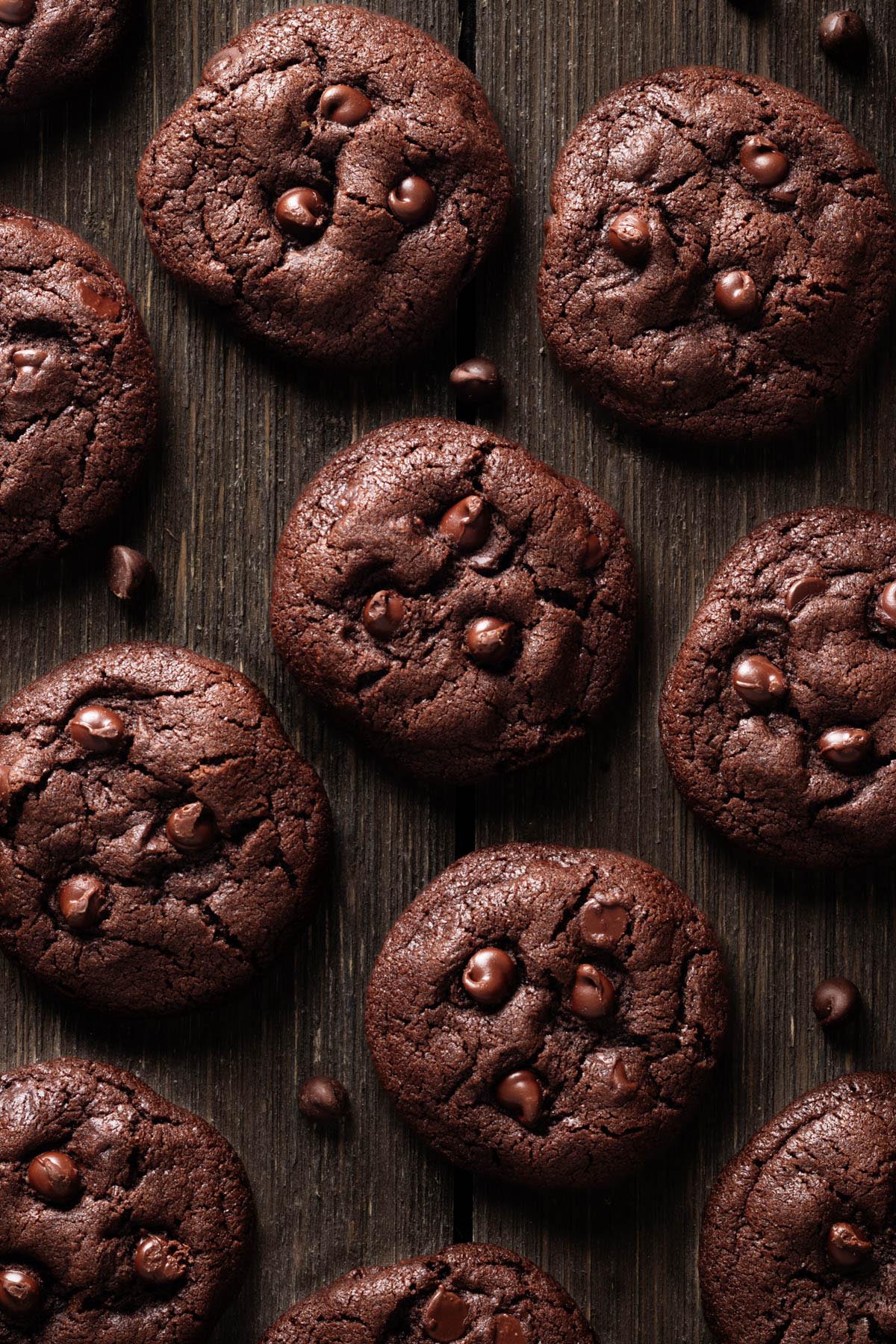 Overhead view of chocolate peanut butter cookies on a rustic wooden surface, showing their cracking tops and melted chocolate chips.