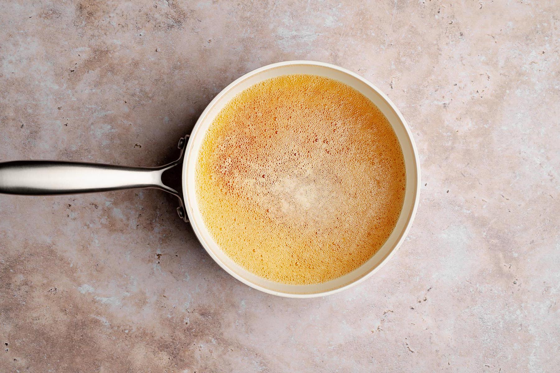 Light-colored saucepan filled with hot, foamy melted butter just beginning to brown on the stovetop.
