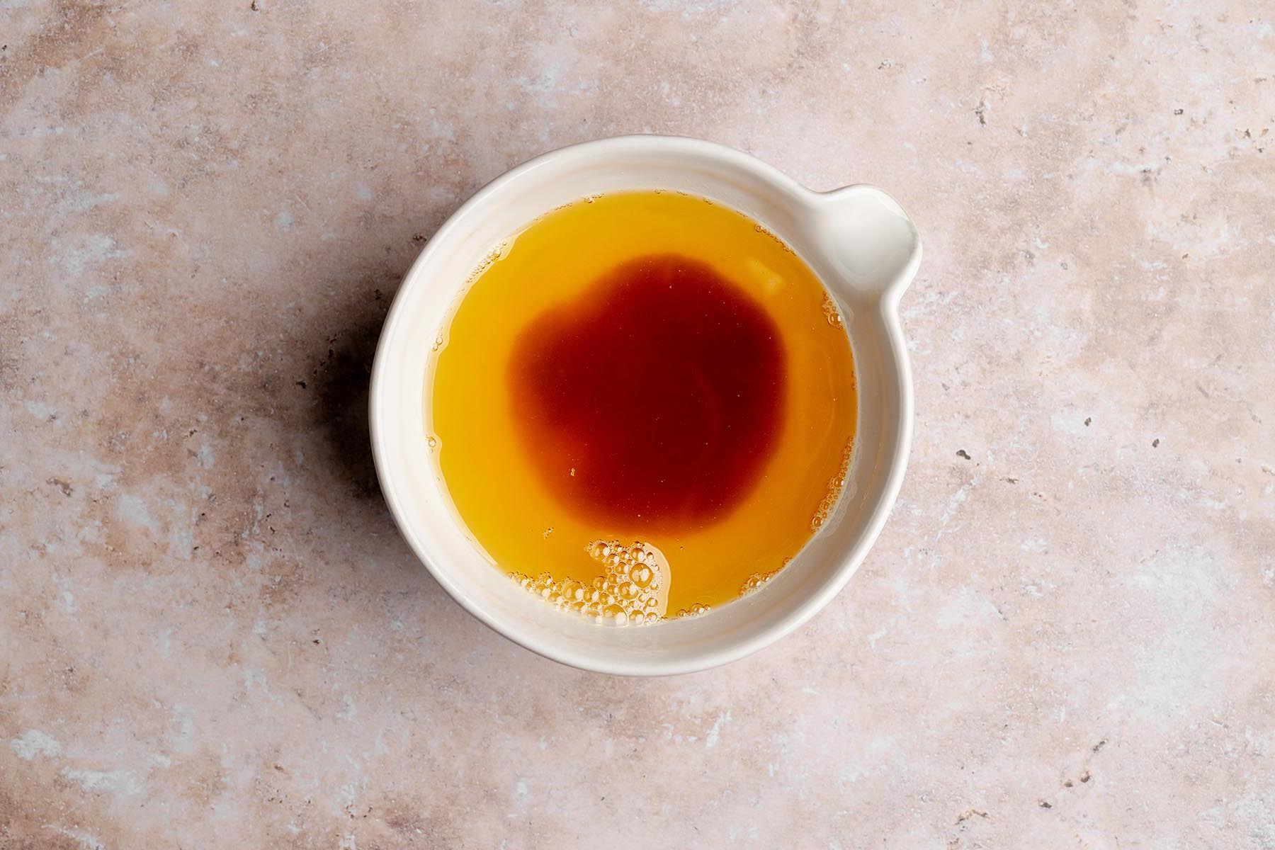 Small cream-colored bowl filled with browned butter, showing a darker caramel-colored center.