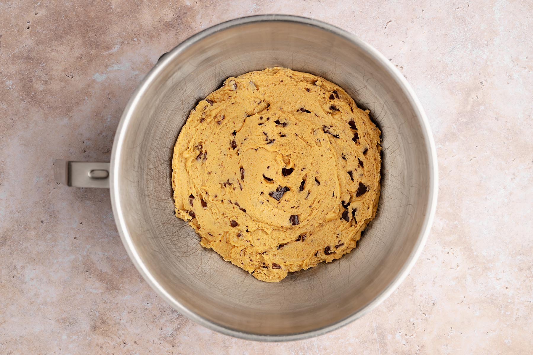 Finished chocolate chunk cookie dough in a mixing bowl with chocolate pieces evenly distributed throughout.