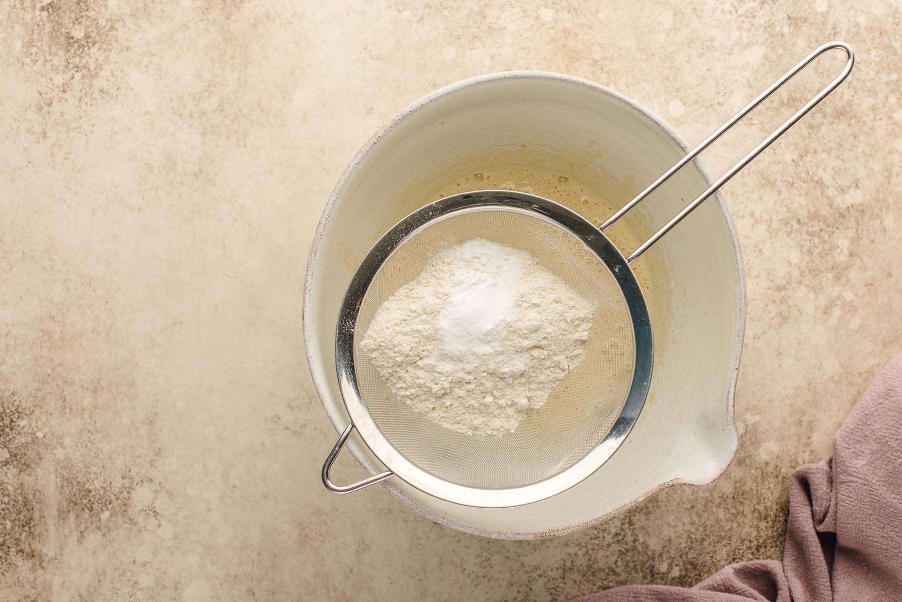 Flour, baking powder, and salt being sifted into the bowl.