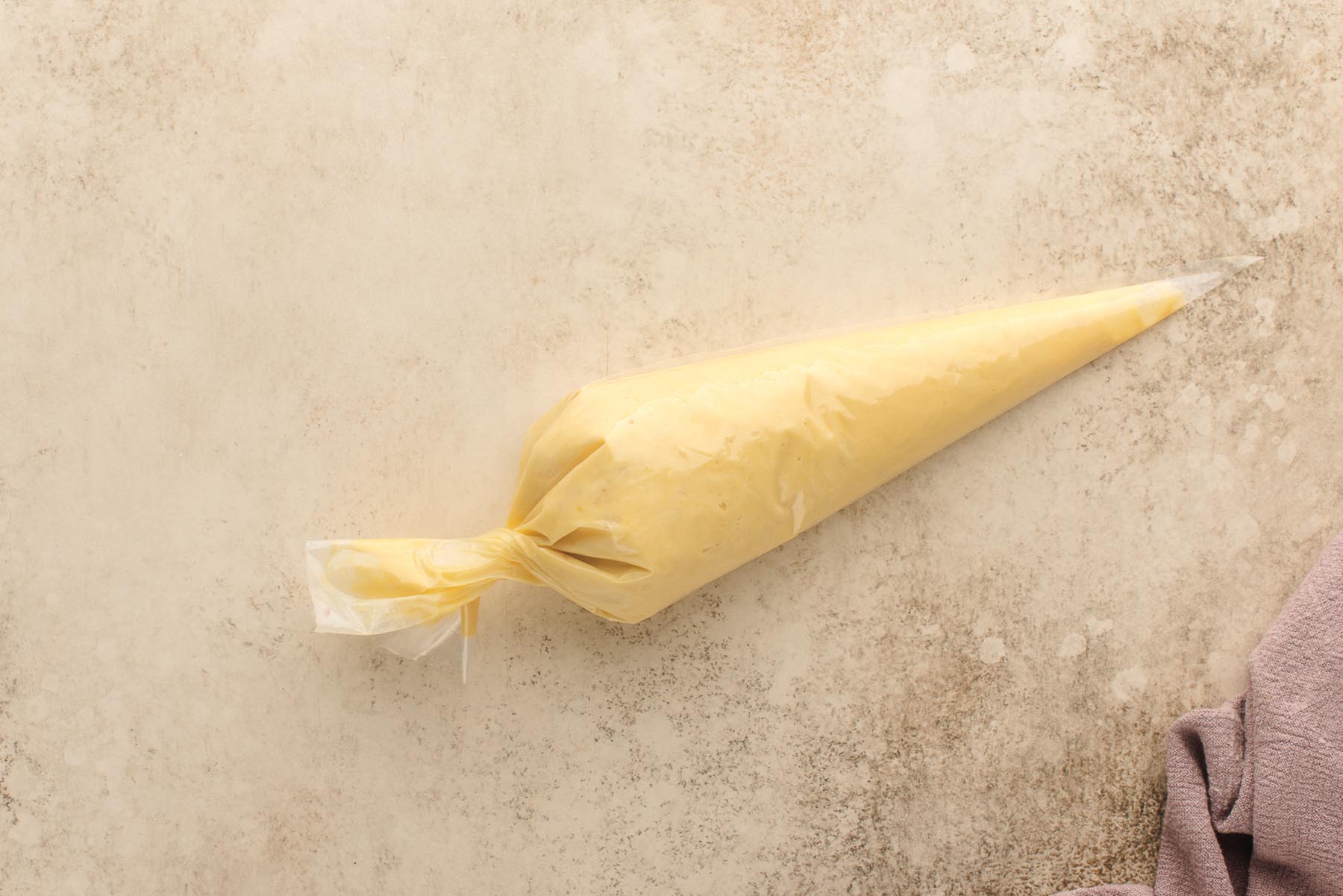 Piping bag filled with madeleine batter, tied and ready to chill.