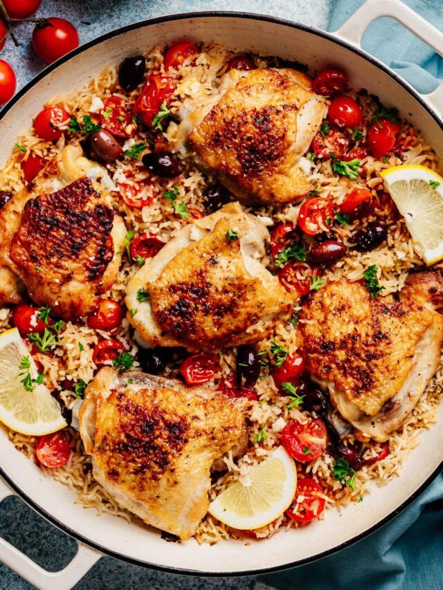 Greek Chicken and Rice in a wide skillet—crispy thighs with tomatoes, Kalamata olives, parsley, and lemon.