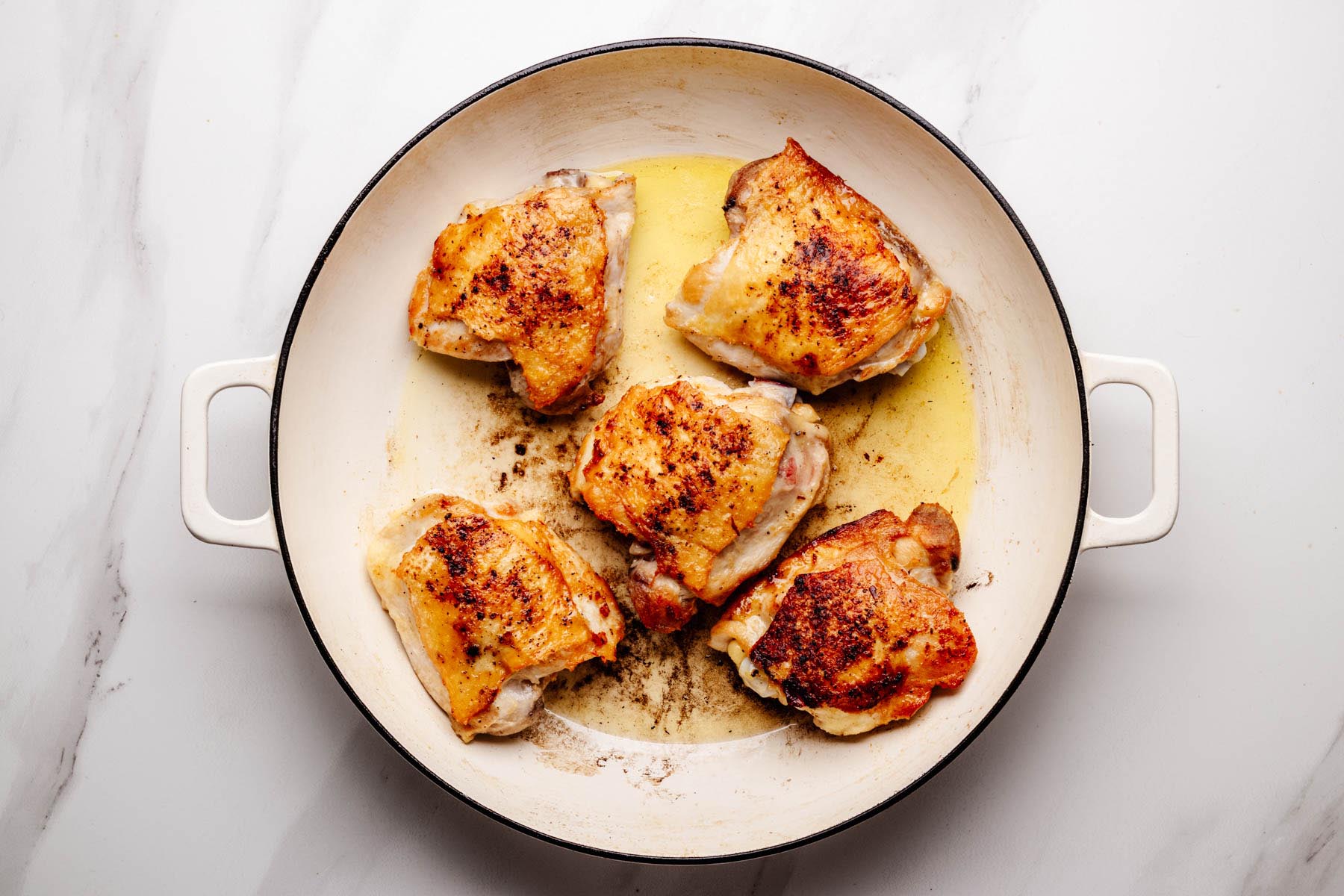 Chicken thighs searing until golden in a large skillet to build flavor for Greek Chicken and Rice.