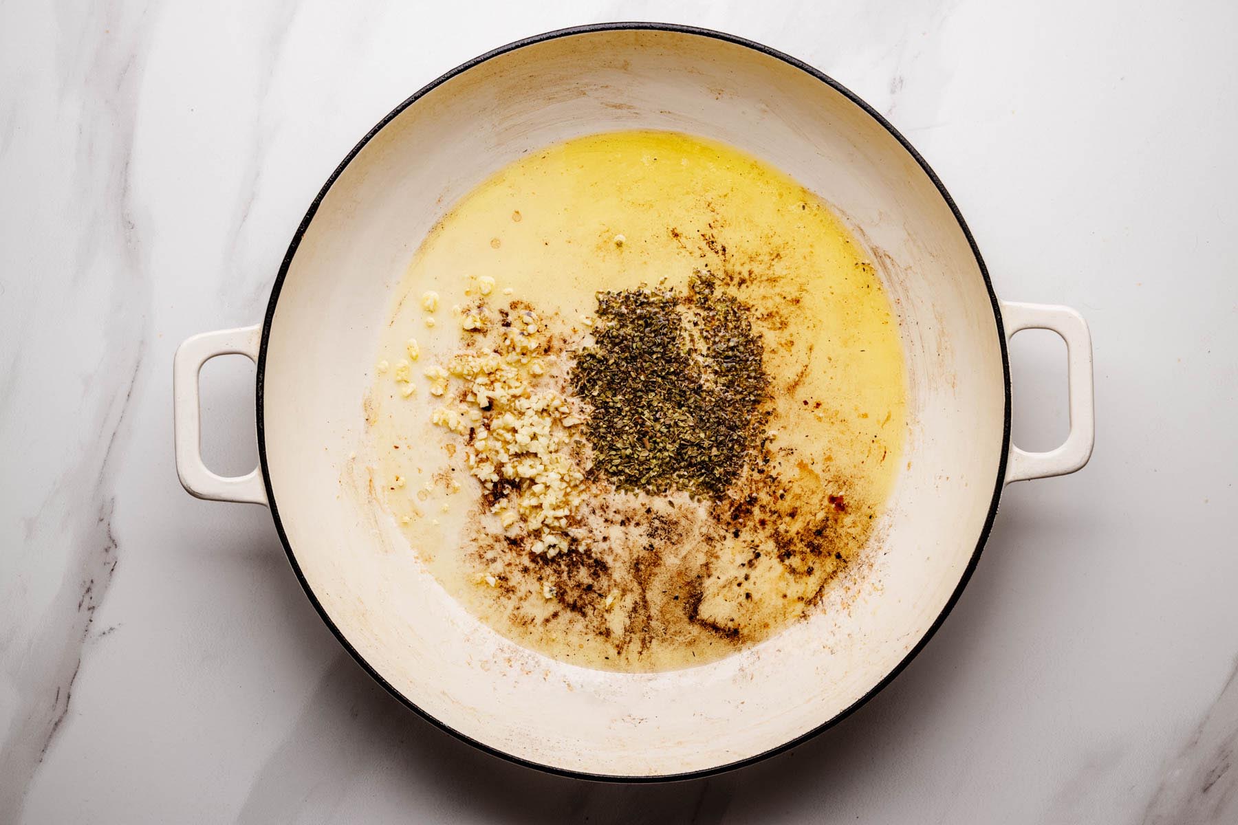 Garlic and dried oregano blooming in pan drippings before adding rice.