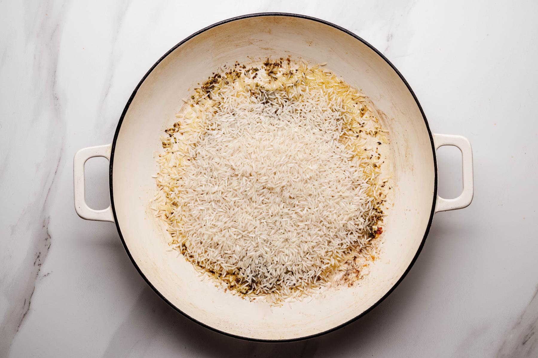 Long-grain white rice added to the skillet and lightly toasted with aromatics.