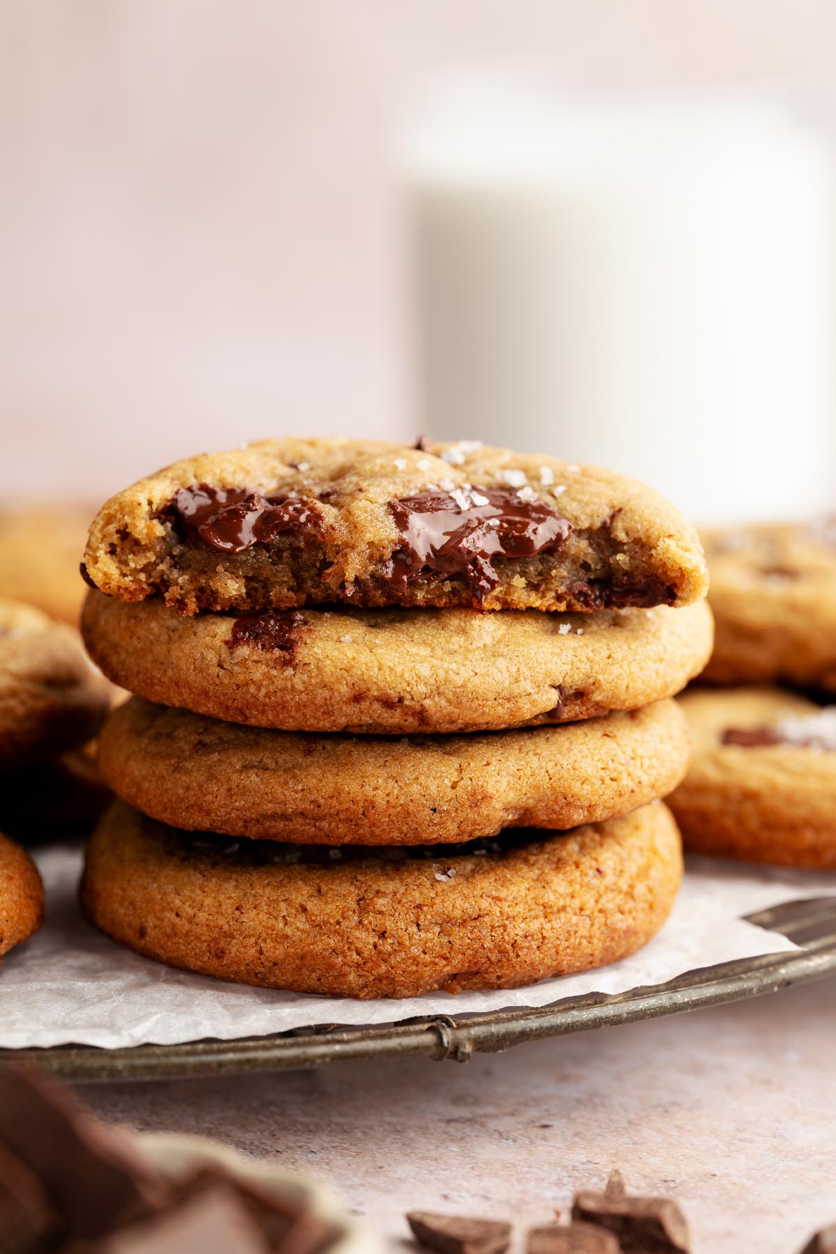 Stack of warm chocolate chunk cookies on a plate, with the top cookie broken open to show the gooey melted chocolate inside.