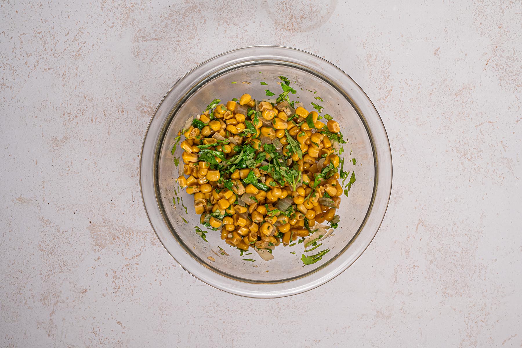 Glass bowl with corn, cilantro, and onions mixed together for the fresh topping.