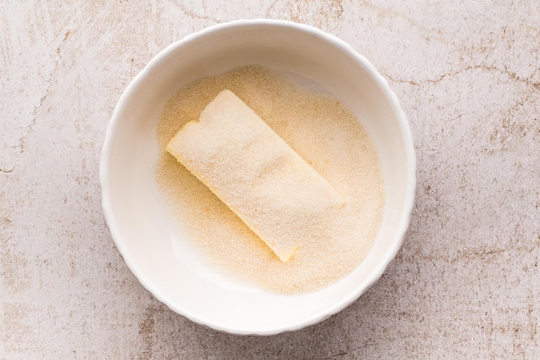 Softened unsalted butter and granulated sugar combined in a bowl before mixing.
