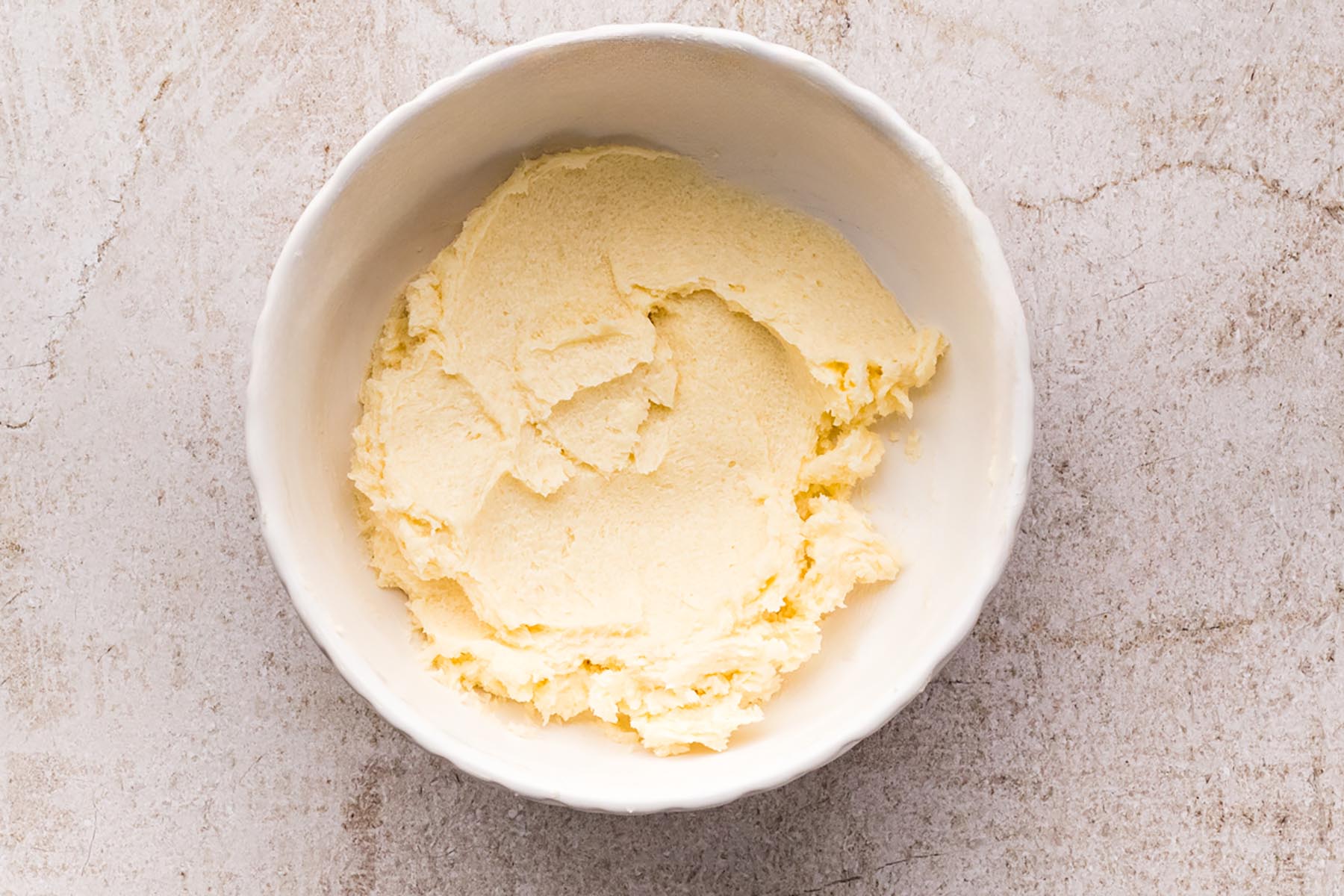 Butter and sugar creamed together in a white bowl until smooth and pale.