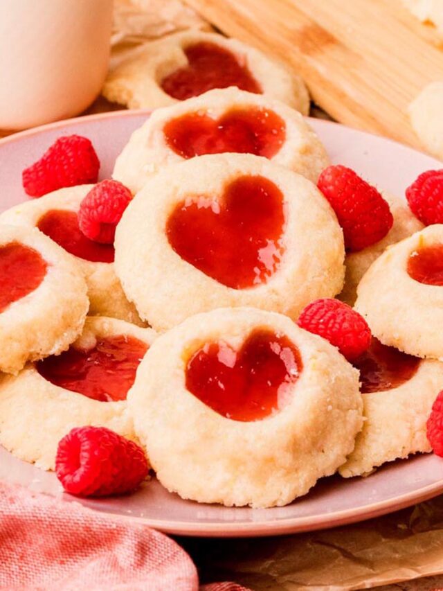 Heart-shaped raspberry thumbprint cookies with buttery shortbread dough and jam centers.