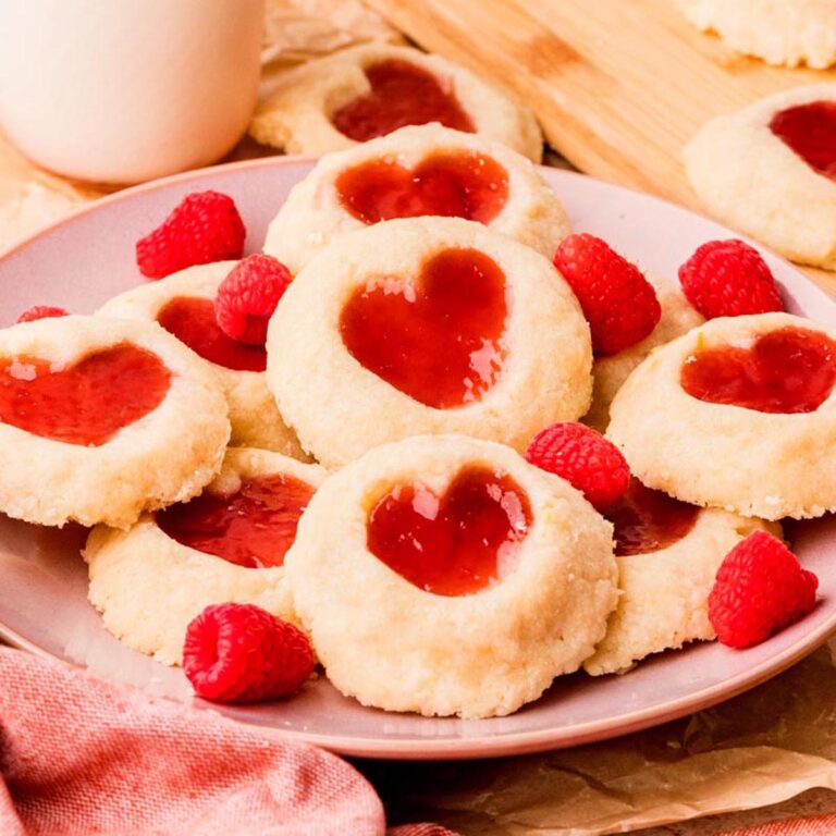 Heart-shaped raspberry thumbprint cookies with buttery shortbread dough and jam centers.