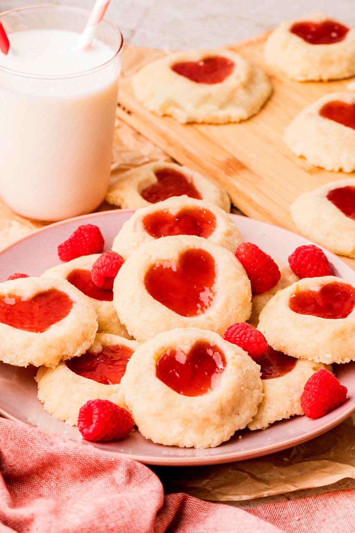 Plate of heart-shaped raspberry thumbprint cookies with jam centers, ready to serve.