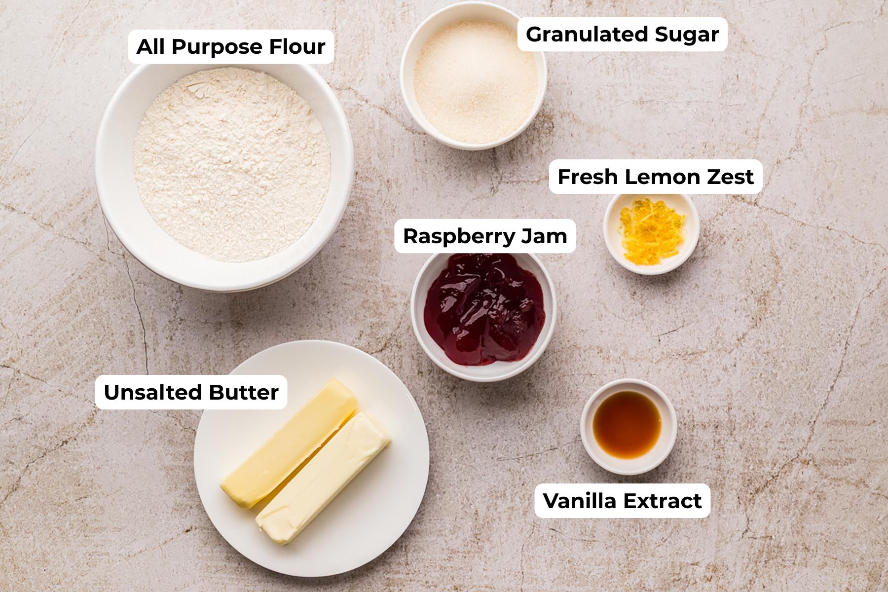 Ingredients for raspberry thumbprint cookies, including flour, butter, sugar, raspberry jam, lemon zest, and vanilla extract arranged on a light surface.