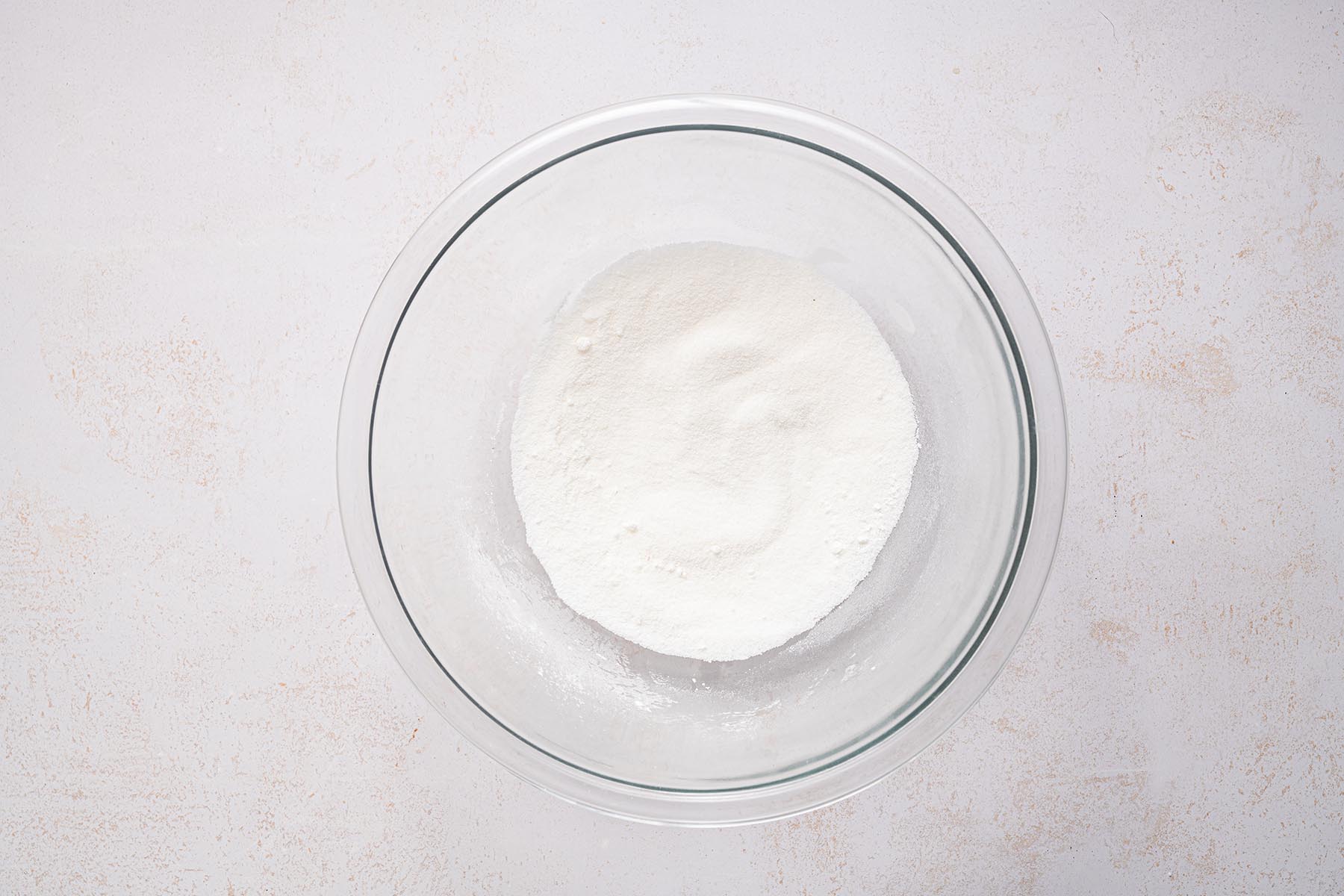 Granulated sugar and cornstarch mixed in a glass bowl.