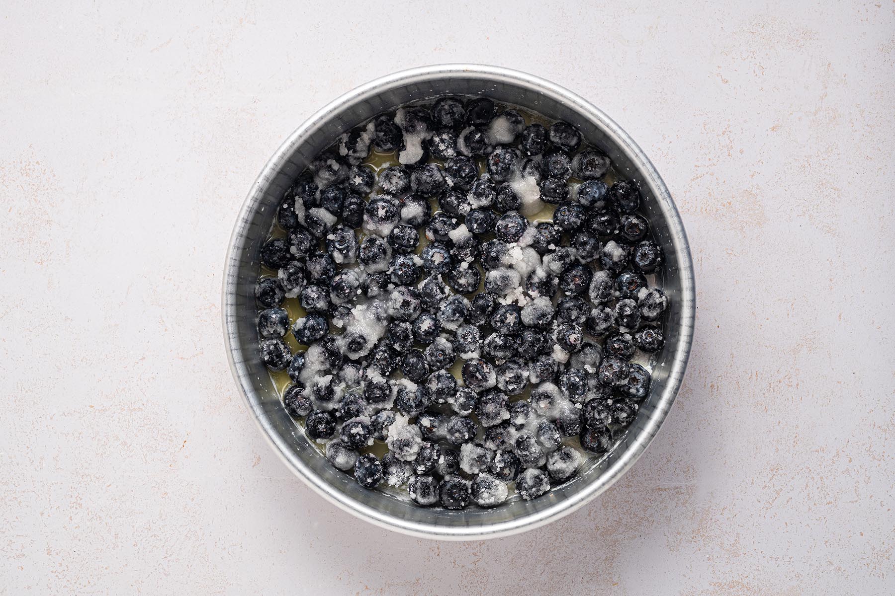 Blueberry topping spread in a buttered cake pan.