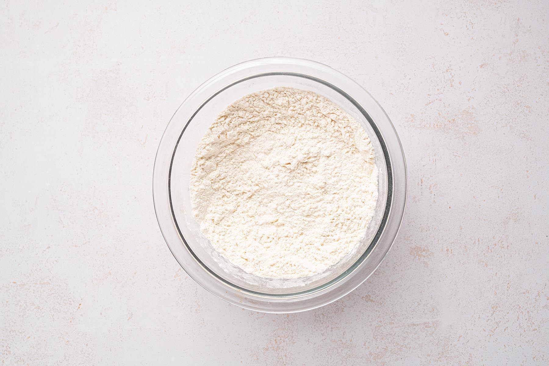Flour, baking powder, and salt whisked together in a glass bowl.