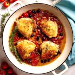 Chicken Provençal with crispy chicken thighs, cherry tomatoes, olives, and herbs simmered in a skillet.