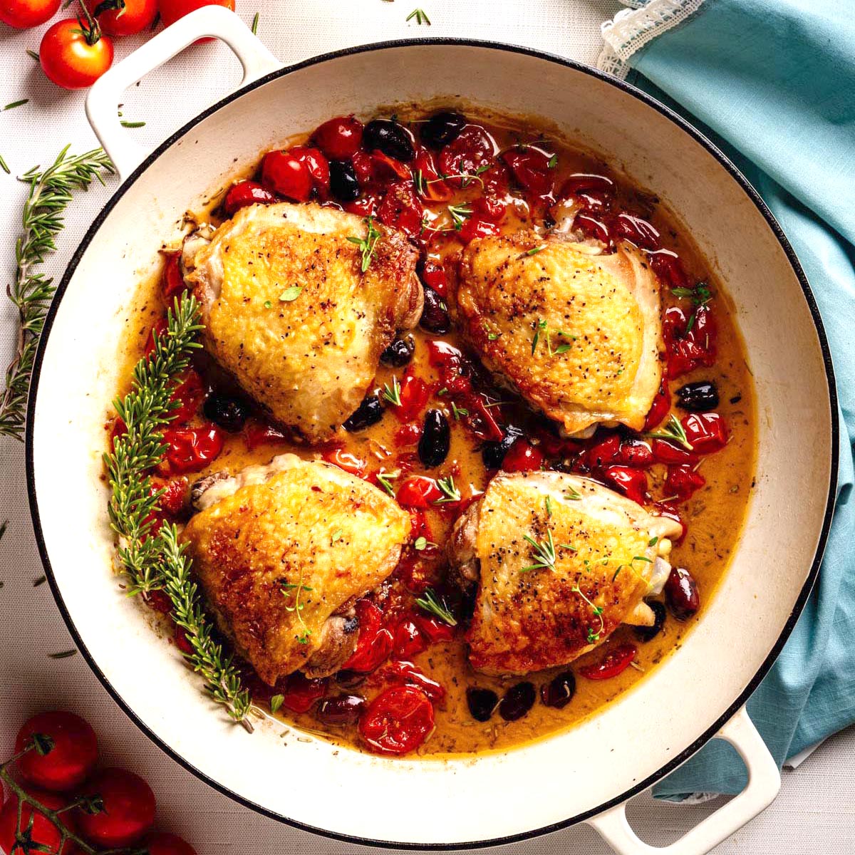 Chicken Provençal with crispy chicken thighs, cherry tomatoes, olives, and herbs simmered in a skillet.