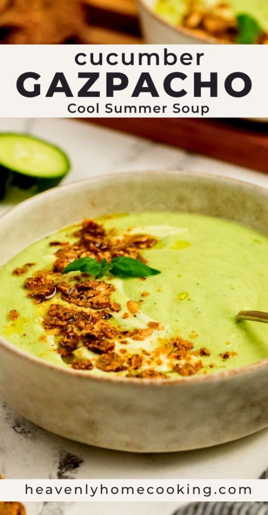 Creamy cucumber gazpacho topped with crunchy garnish and fresh basil in a ceramic bowl. Vertical Pinterest pin for a cool and refreshing cucumber gazpacho summer soup recipe from Heavenly Home Cooking.