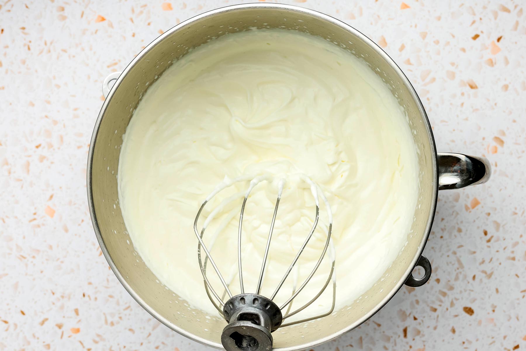 Whipped heavy cream in the bowl of a stand mixer.