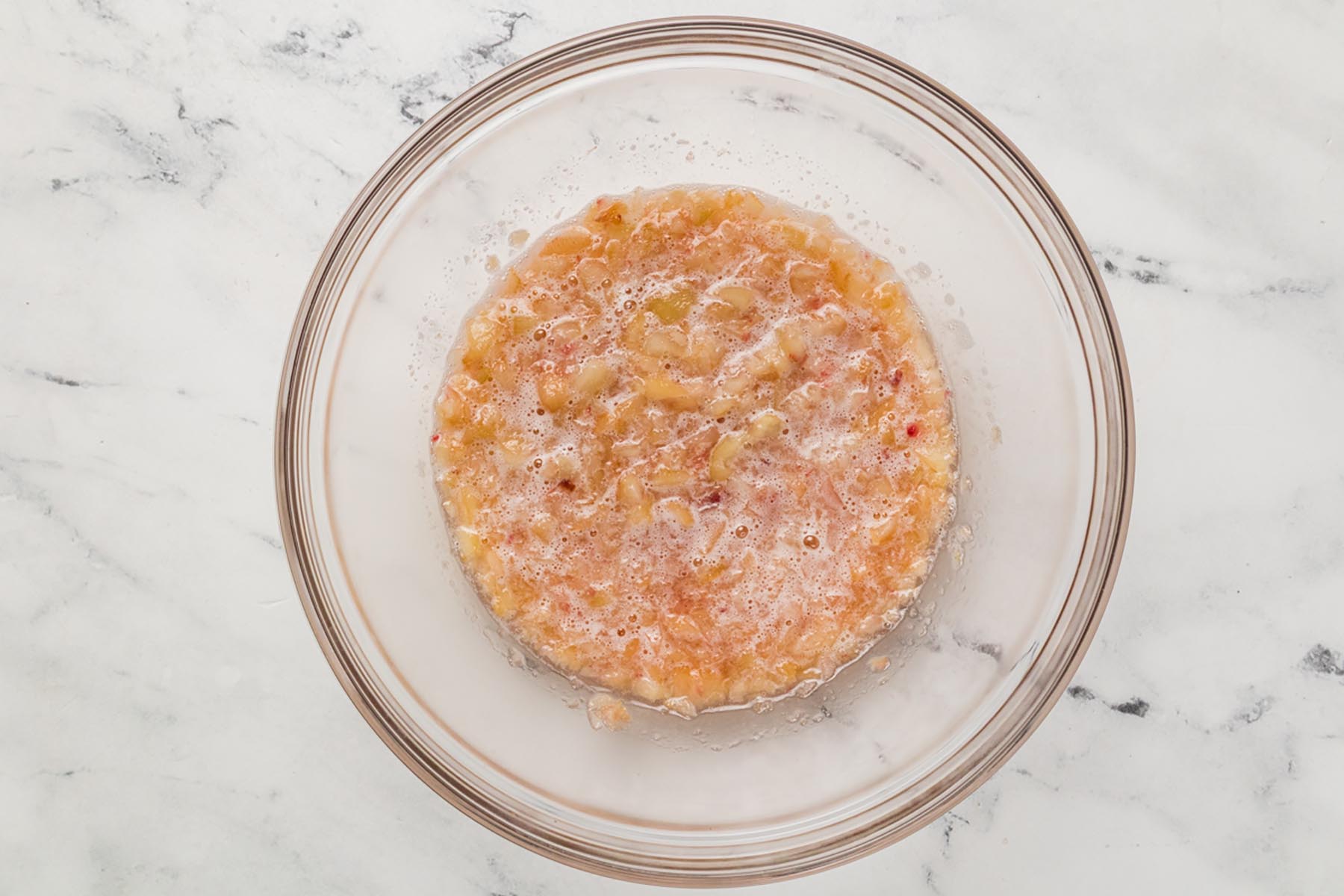 Blended peach puree in a glass bowl prepared for easy peach ice cream recipe.