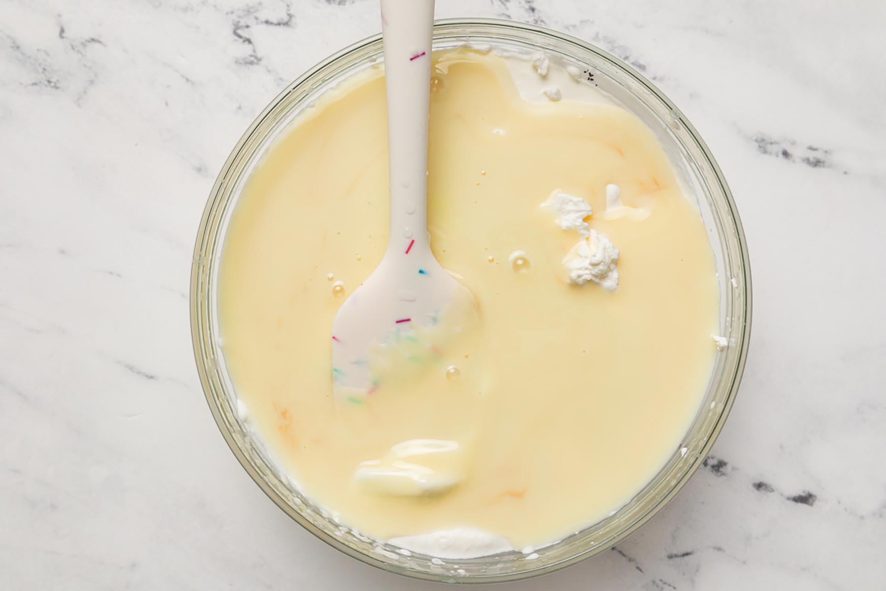 Whipped cream being folded into the peach ice cream base for a smooth and creamy frozen dessert.