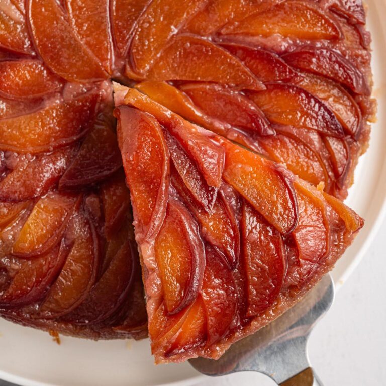 Close-up of upside down cake with peaches arranged in a glossy caramelized spiral pattern.