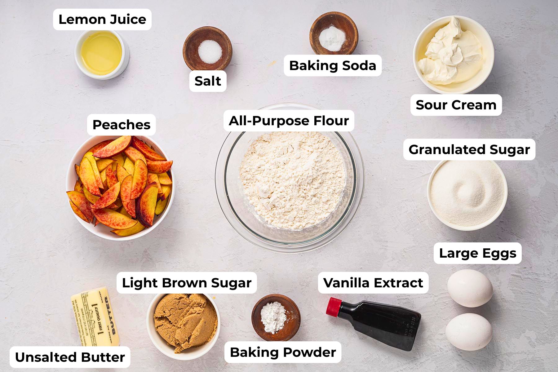 Labeled ingredients for an upside-down cake with peaches including peaches, flour, sugar, sour cream, eggs, and butter.
