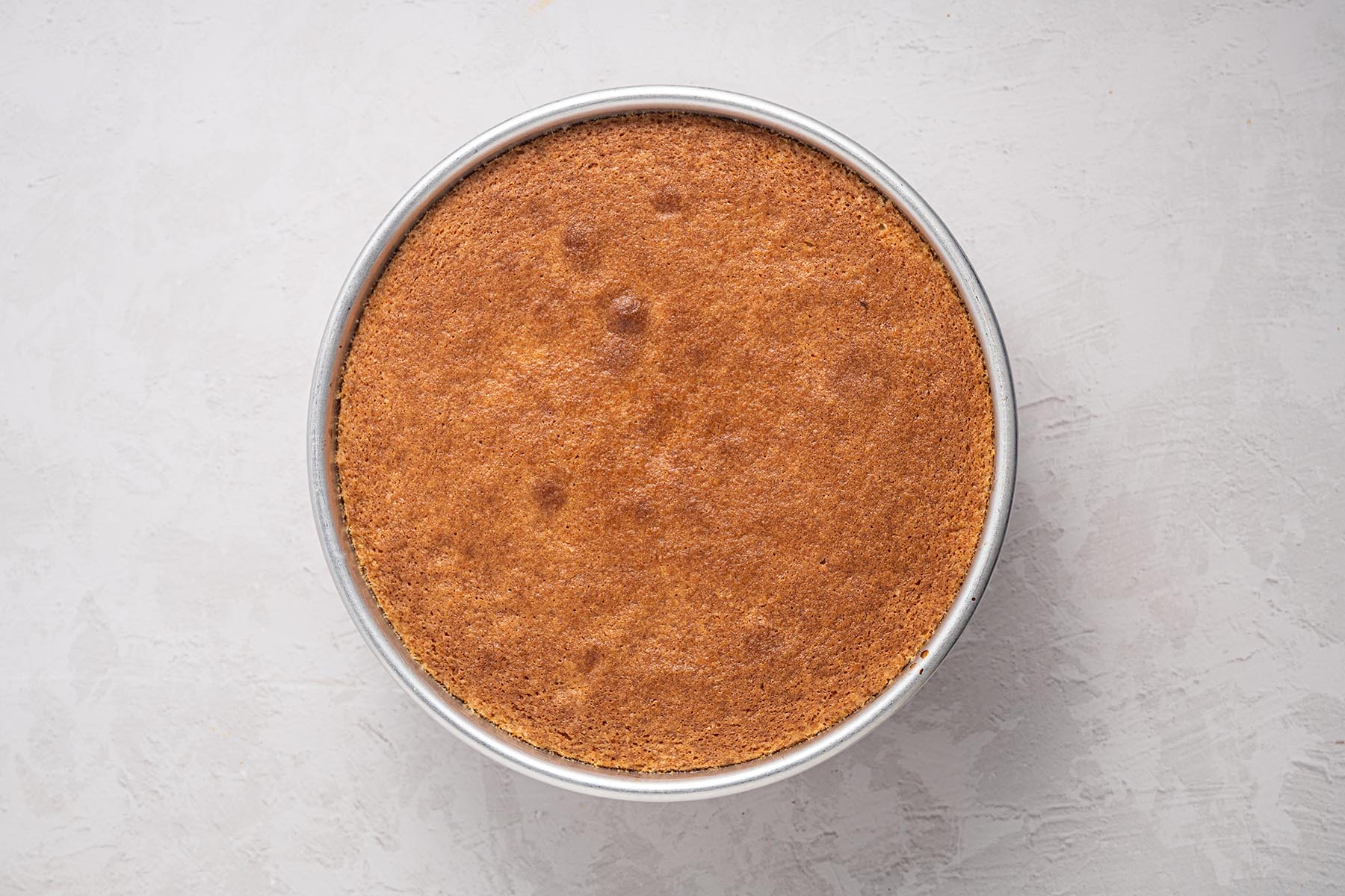 Freshly baked peach cake in a round cake pan.