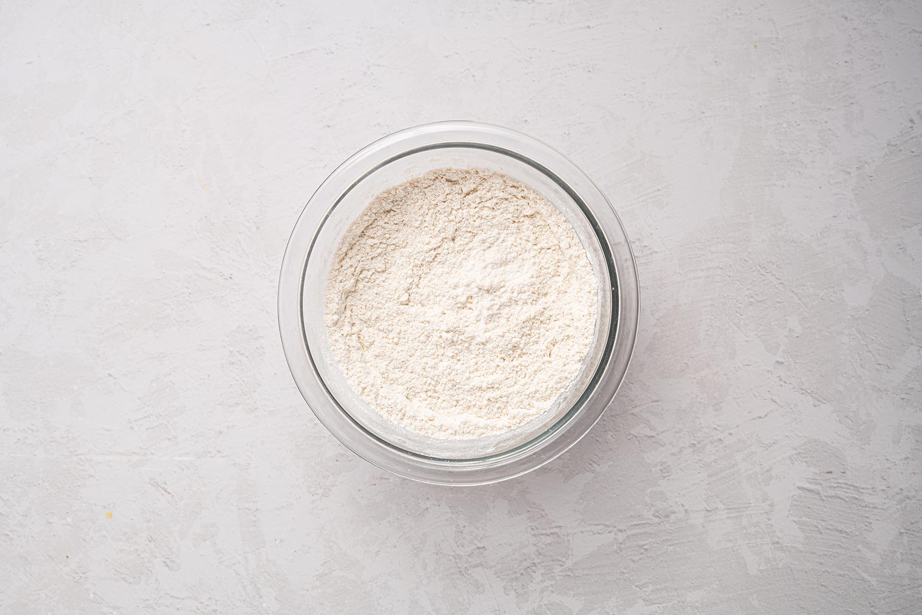 Flour mixture in a clear glass mixing bowl.