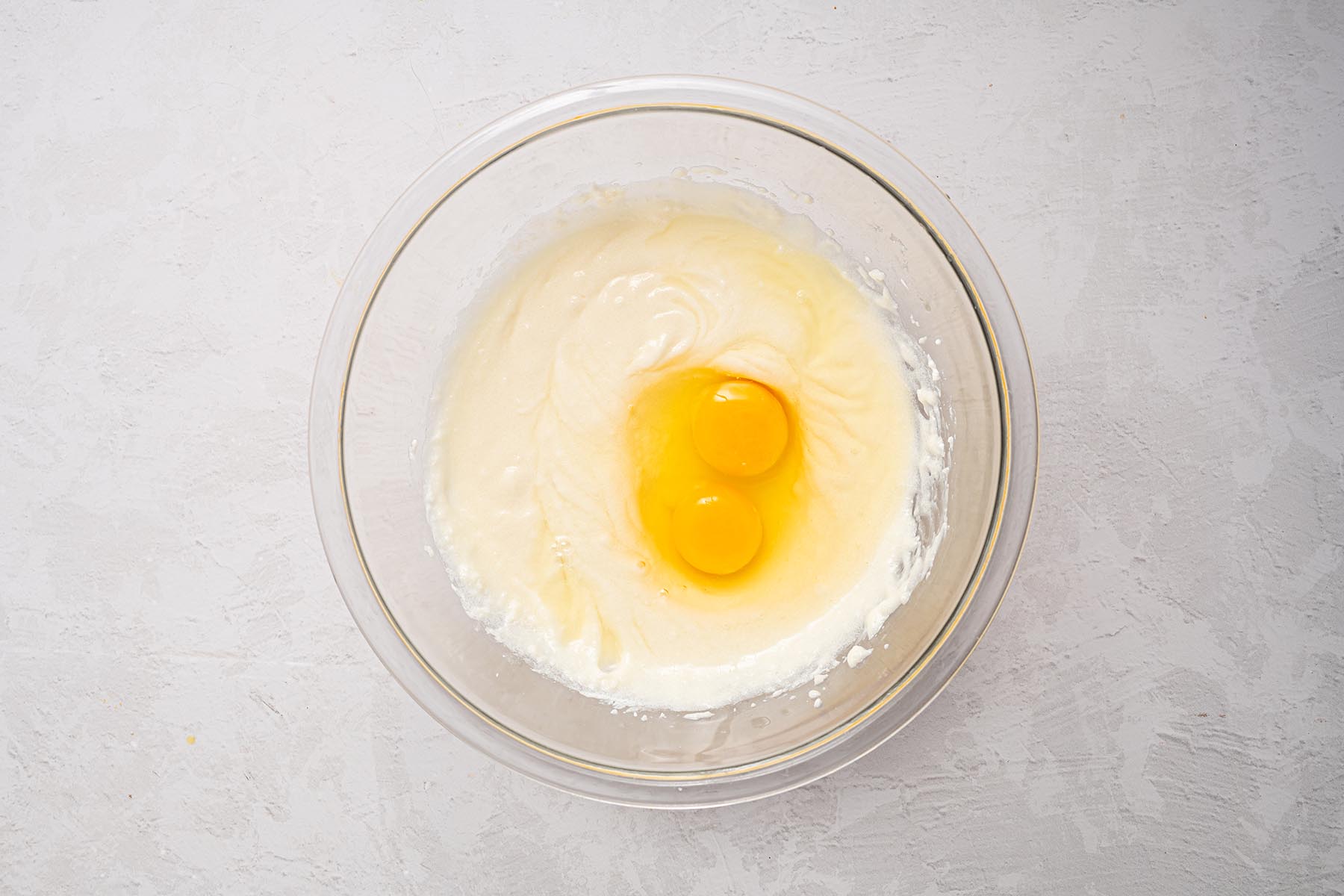 Cake batter mixture with eggs added to the bowl.