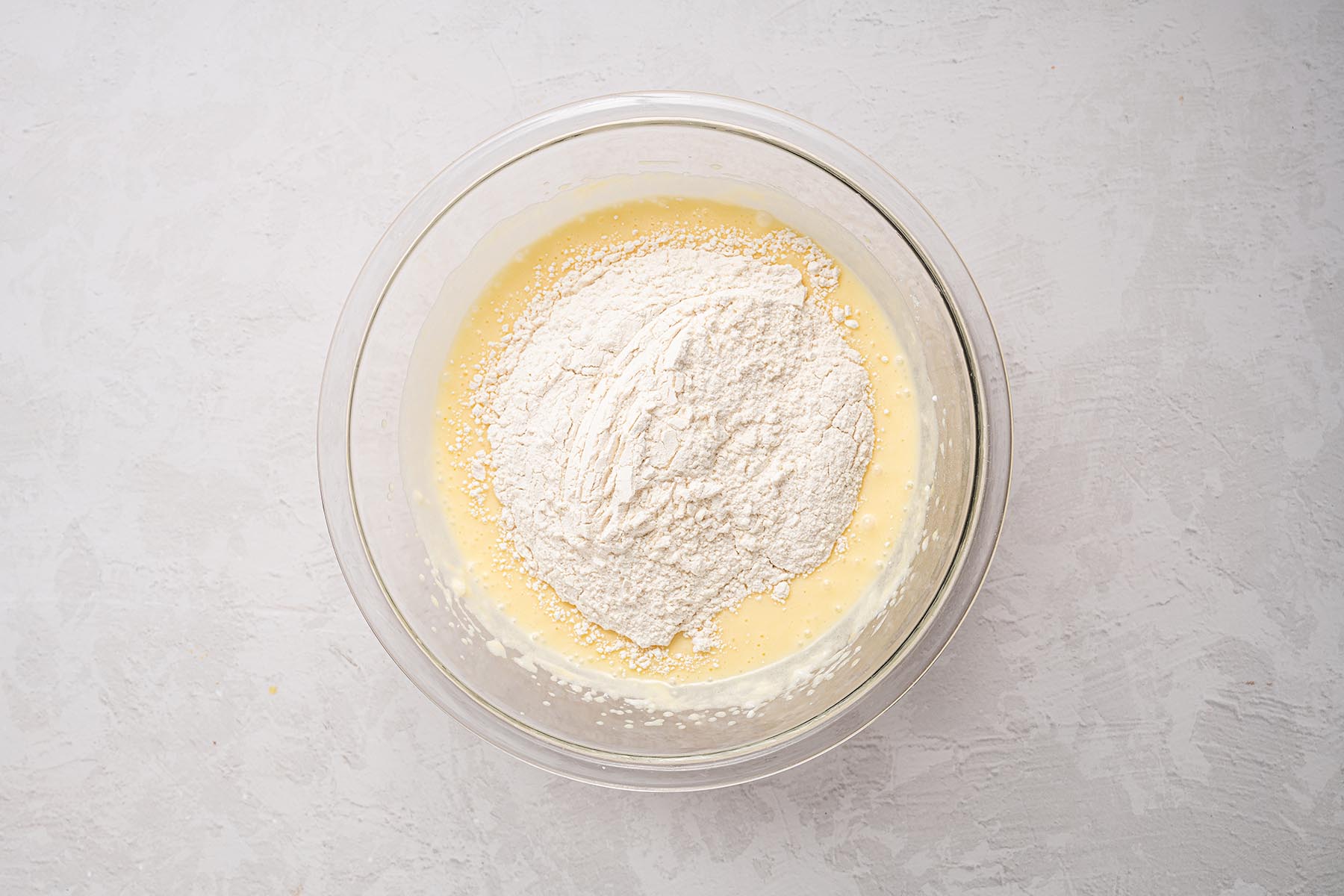 Flour mixture added to wet ingredients while making fresh peach cake batter.