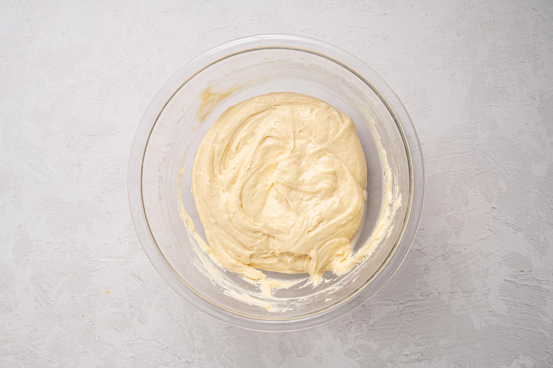 Smooth vanilla cake batter in a glass mixing bowl.