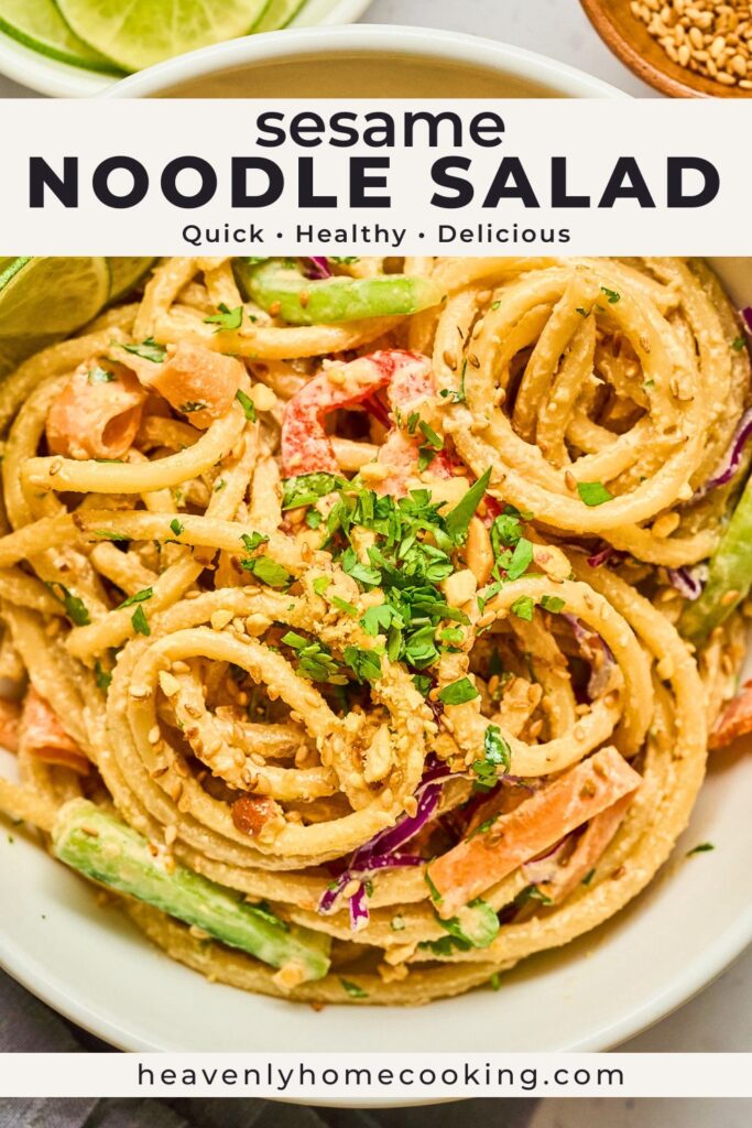 Close-up sesame noodle salad with chilled noodles, sesame dressing, cucumbers, carrots, cabbage, lime wedges, and fresh herbs in a white bowl. Vertical Pinterest pin for a quick and healthy noodle salad recipe from Heavenly Home Cooking.