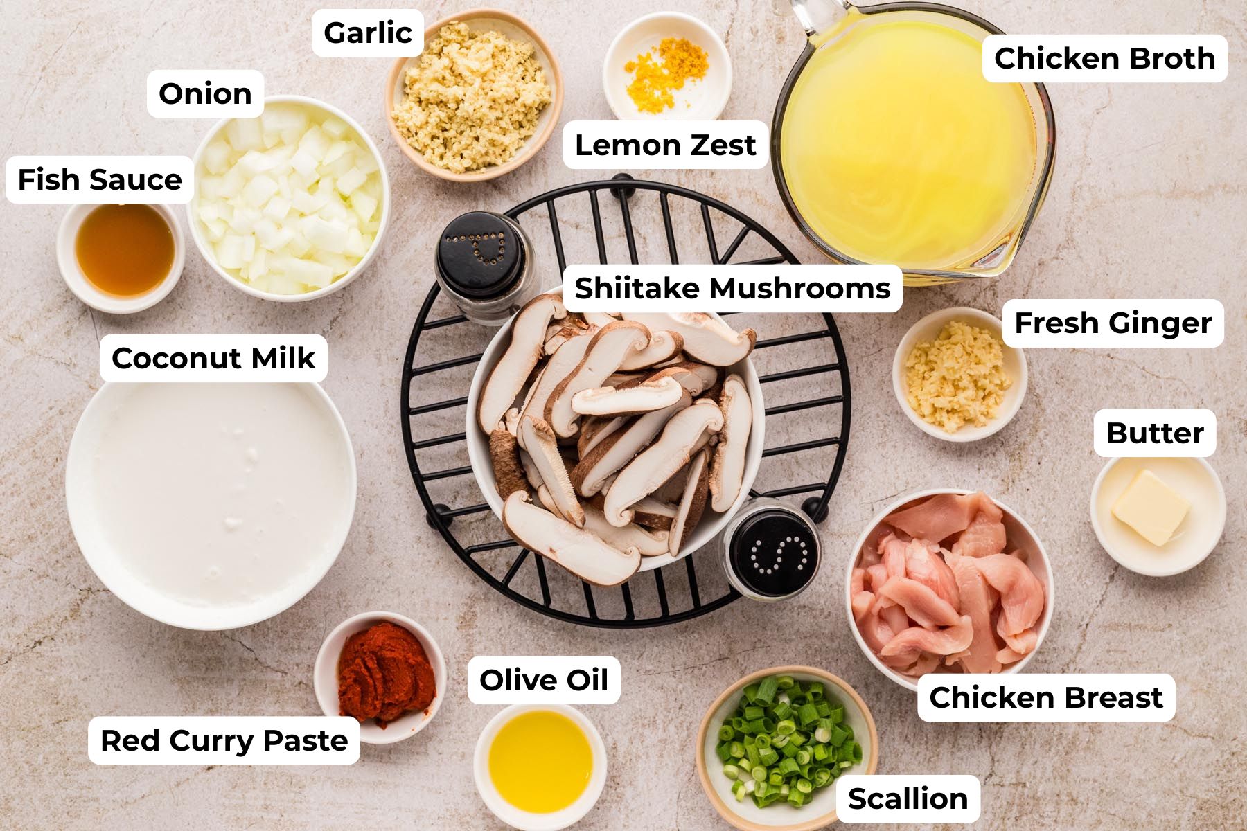 Ingredients for Thai chicken curry soup including chicken broth, coconut milk, shiitake mushrooms, chicken, garlic, ginger, onion, fish sauce, and red curry paste