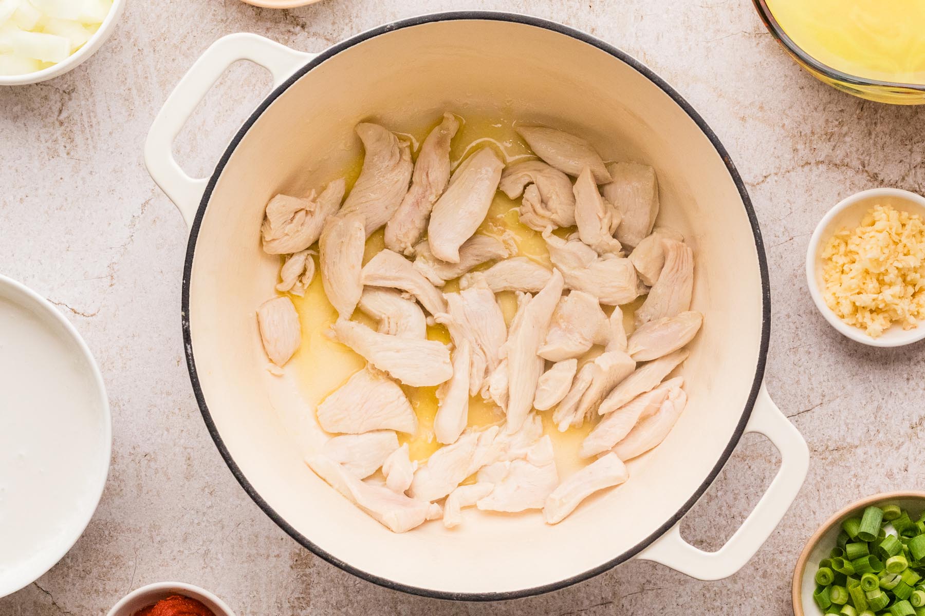 Chicken breast pieces cooking in oil and butter for coconut curry soup.