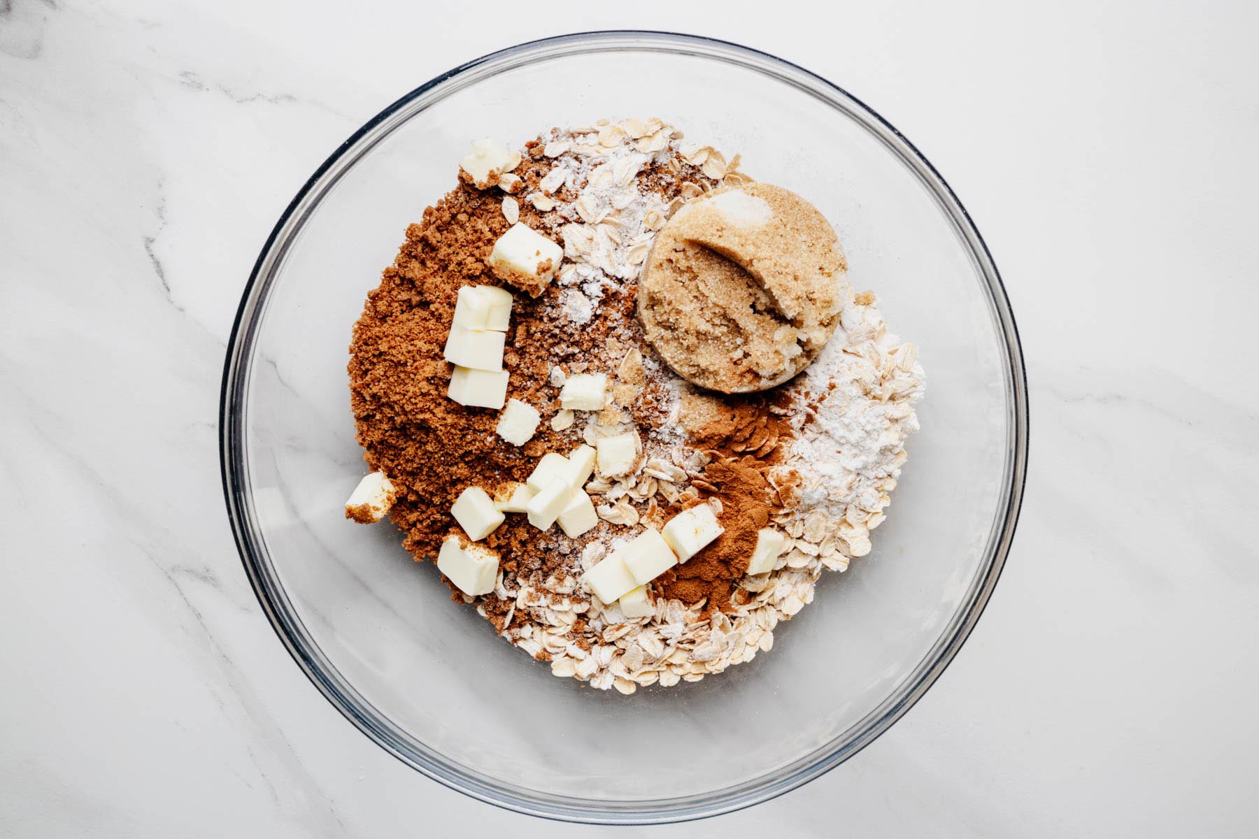 Ginger snap crumbs, oats, brown sugar, flour, cinnamon, salt, and cubed butter in a mixing bowl.