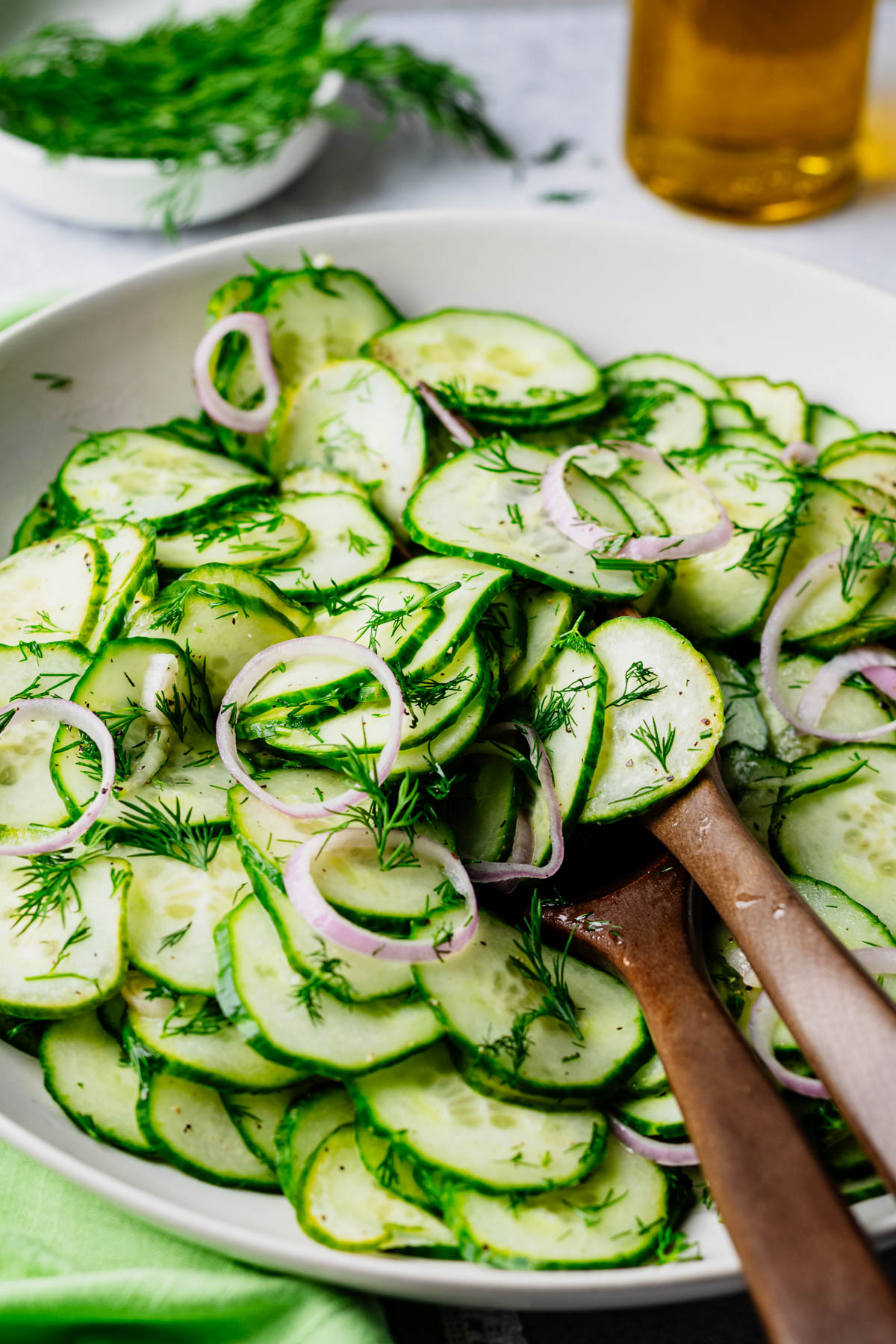 Fresh cucumber dill salad with English cucumbers, dill, and shallot in a light white wine vinaigrette, served in a white bowl.