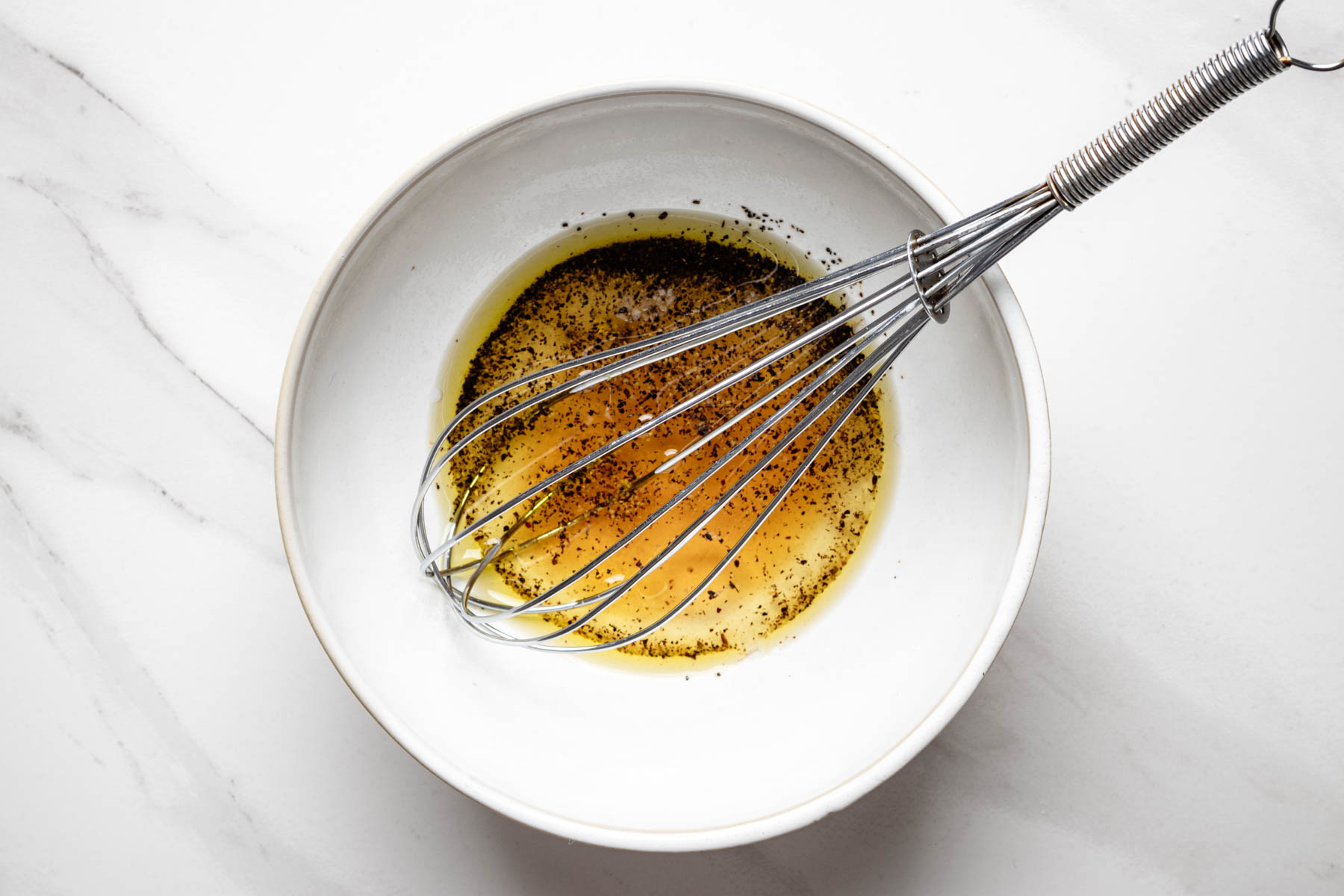 White wine vinegar, olive oil, honey, kosher salt, and black pepper whisked together in a small bowl to make the dressing.