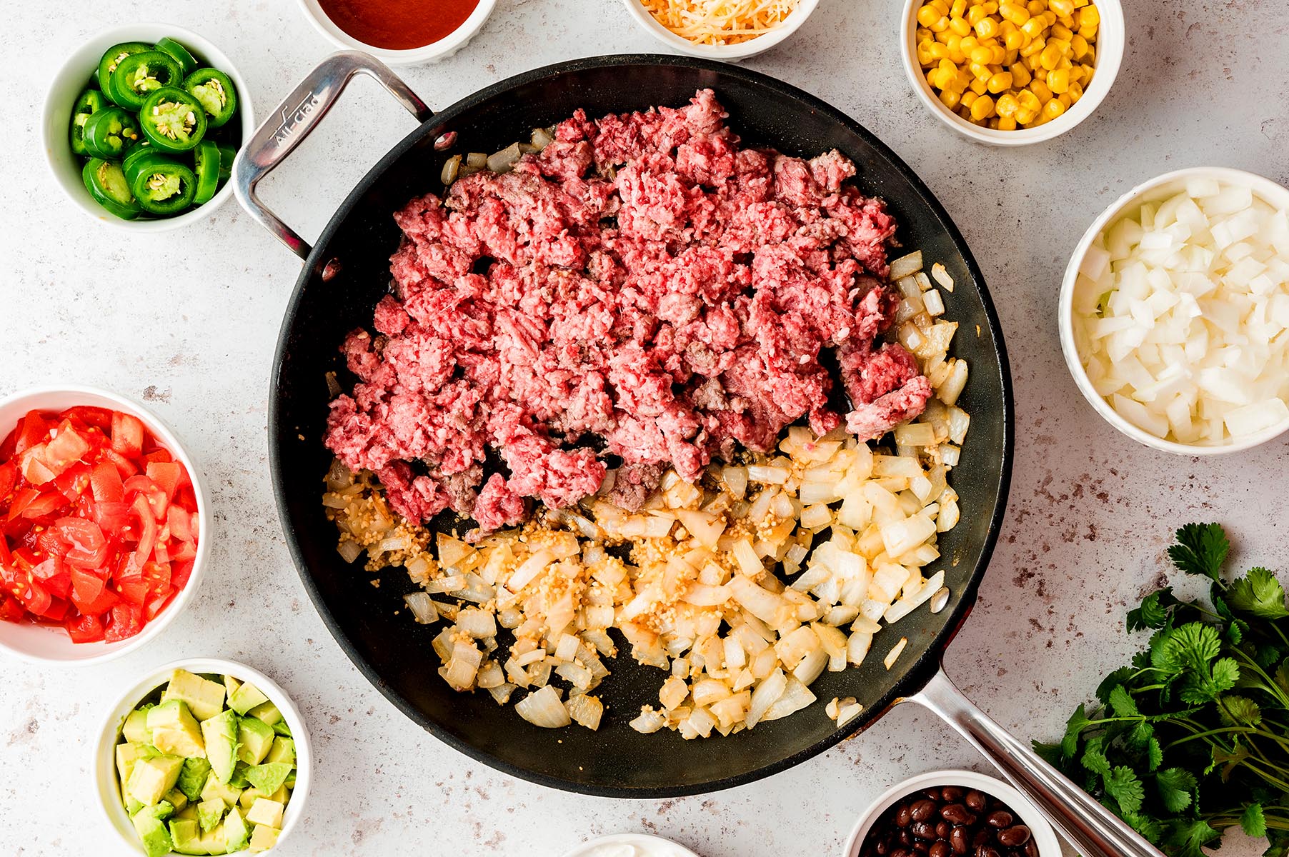 Ground beef added to a skillet with saut&eacute;ed onions and garlic.