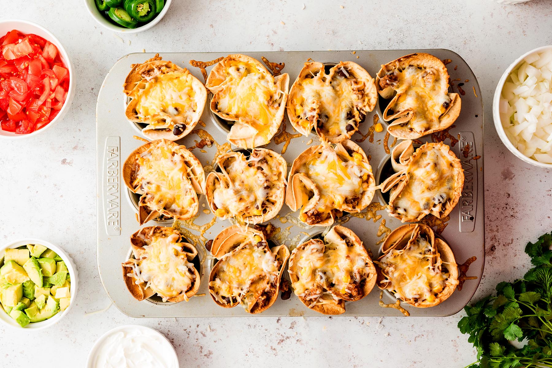 Baked enchilada cups with melted cheese in crispy tortilla shells.
