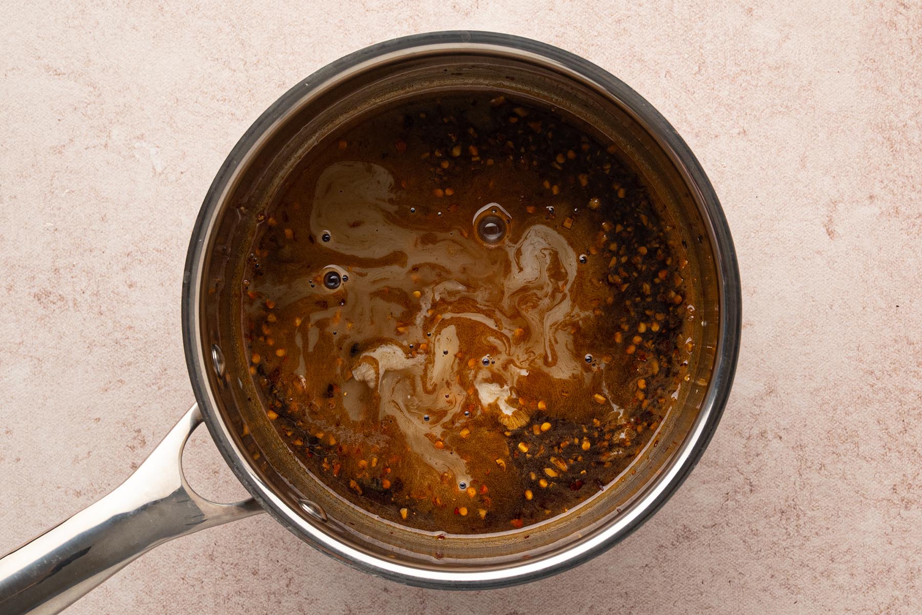 An overhead view of the honey garlic sauce simmering in a saucepan until slightly thickened.