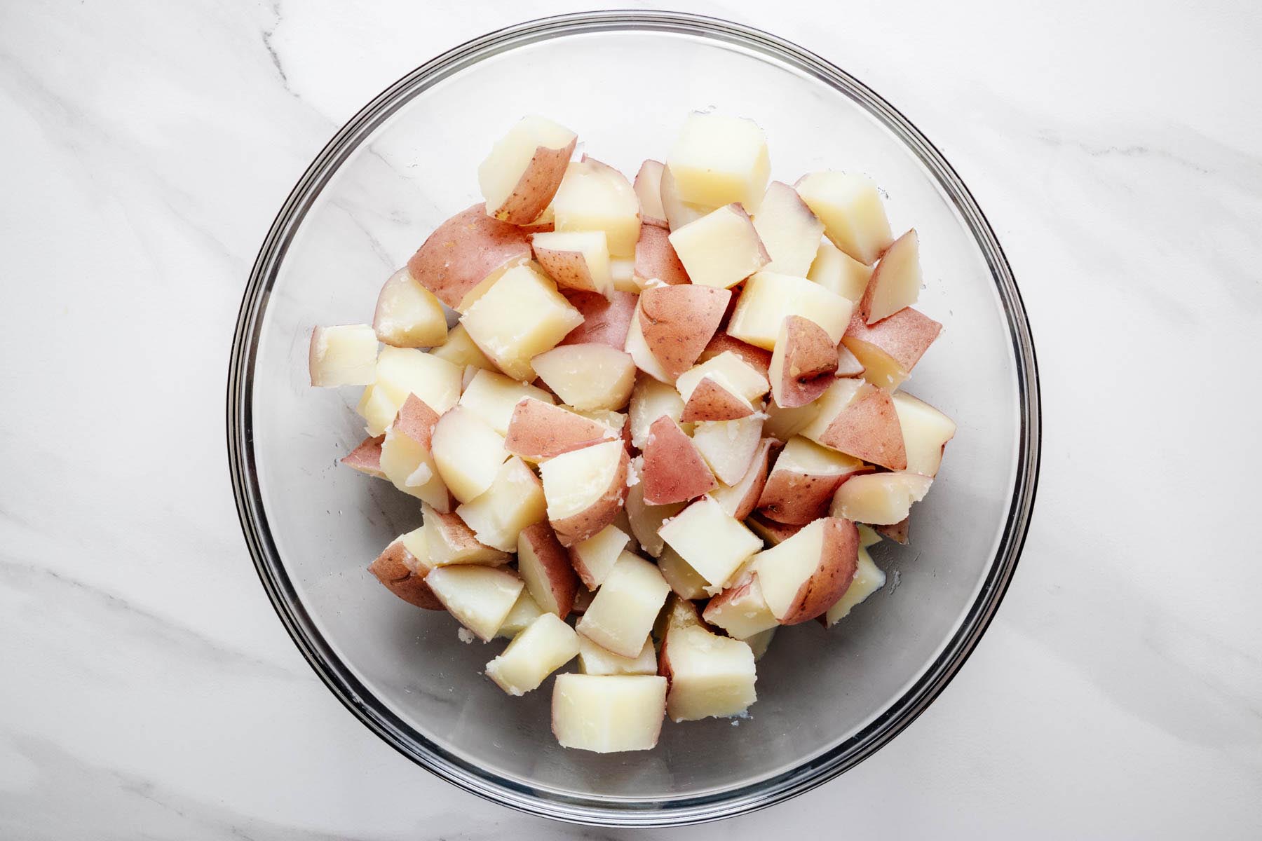 Cooked red potatoes transferred to a large mixing bowl after draining.