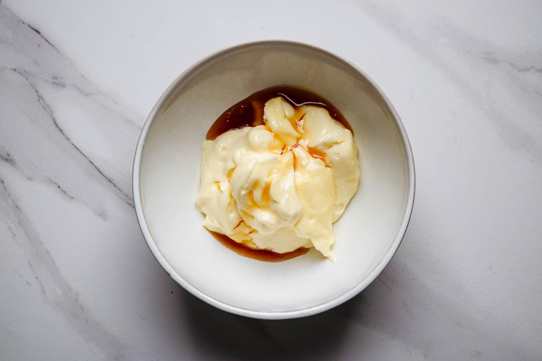 Mayonnaise and honey in a small bowl before being mixed together.