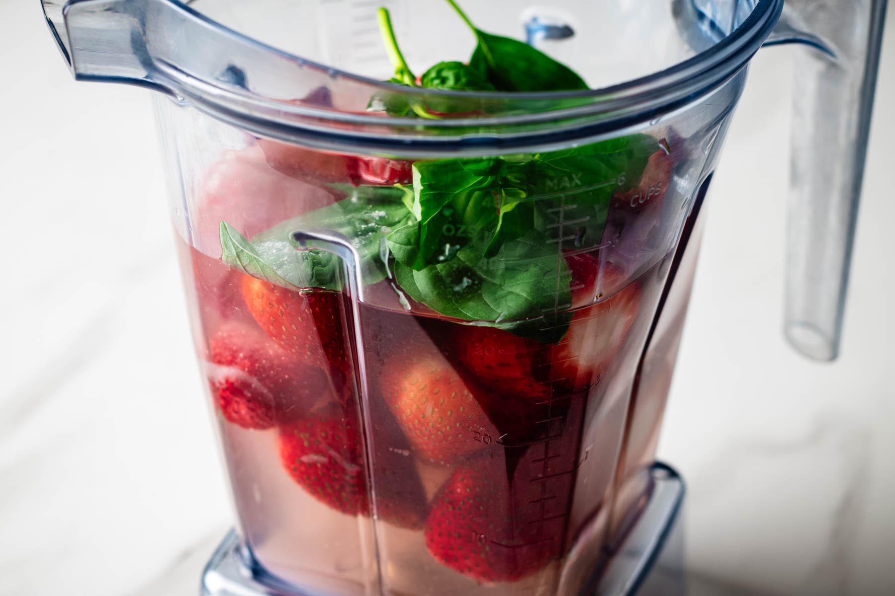 Fresh strawberries, basil leaves, water, sugar, lime juice, and salt added to a blender to make strawberry basil agua fresca.