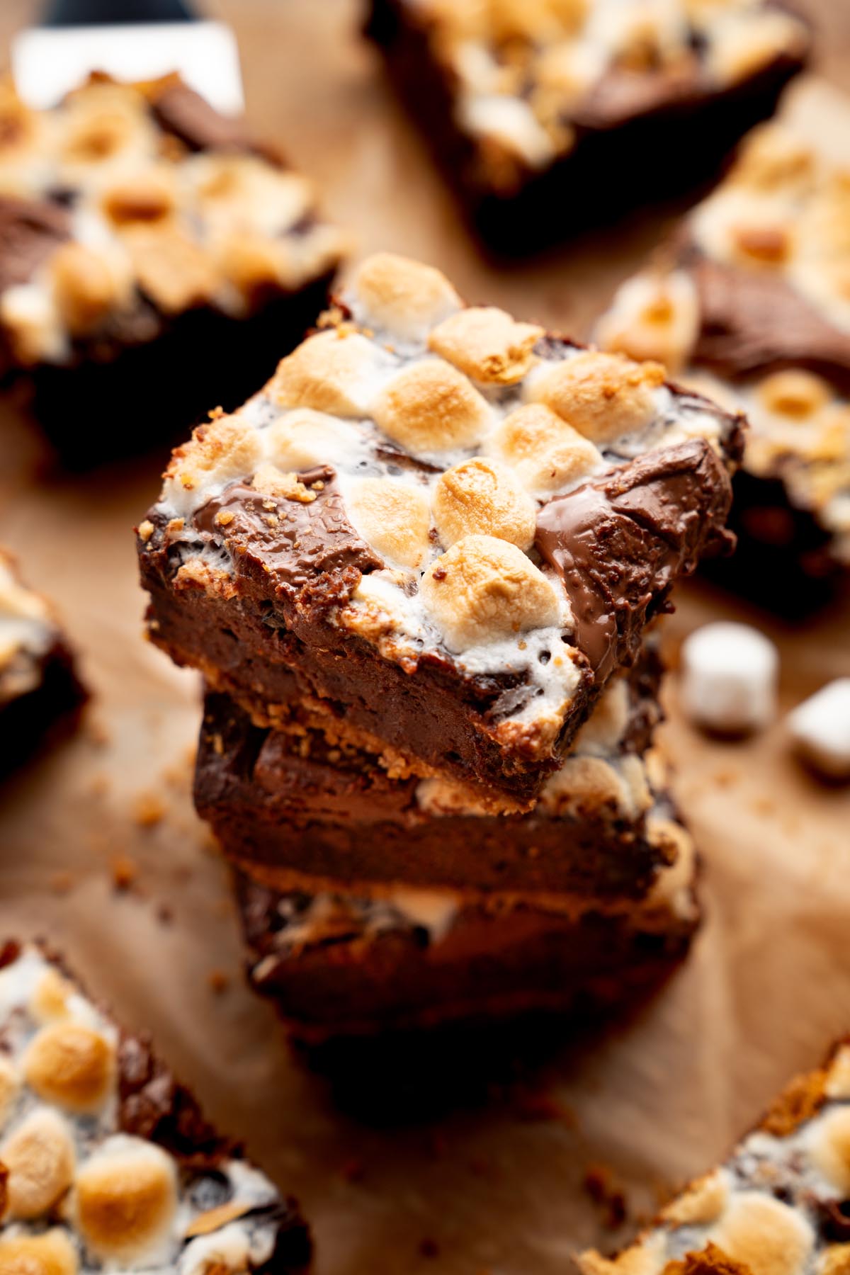 Stack of sweet potato s'mores brownies with toasted mini marshmallows, melted chocolate chunks, and graham cracker crust on a wooden board.