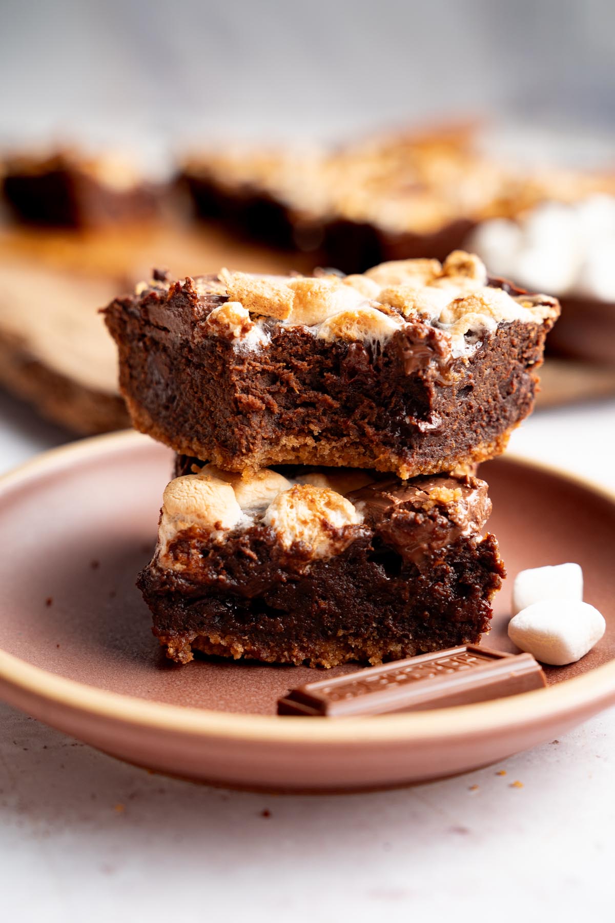 Sweet potato s'mores brownies stacked on a plate, showing the fudgy brownie layer and graham cracker crust.