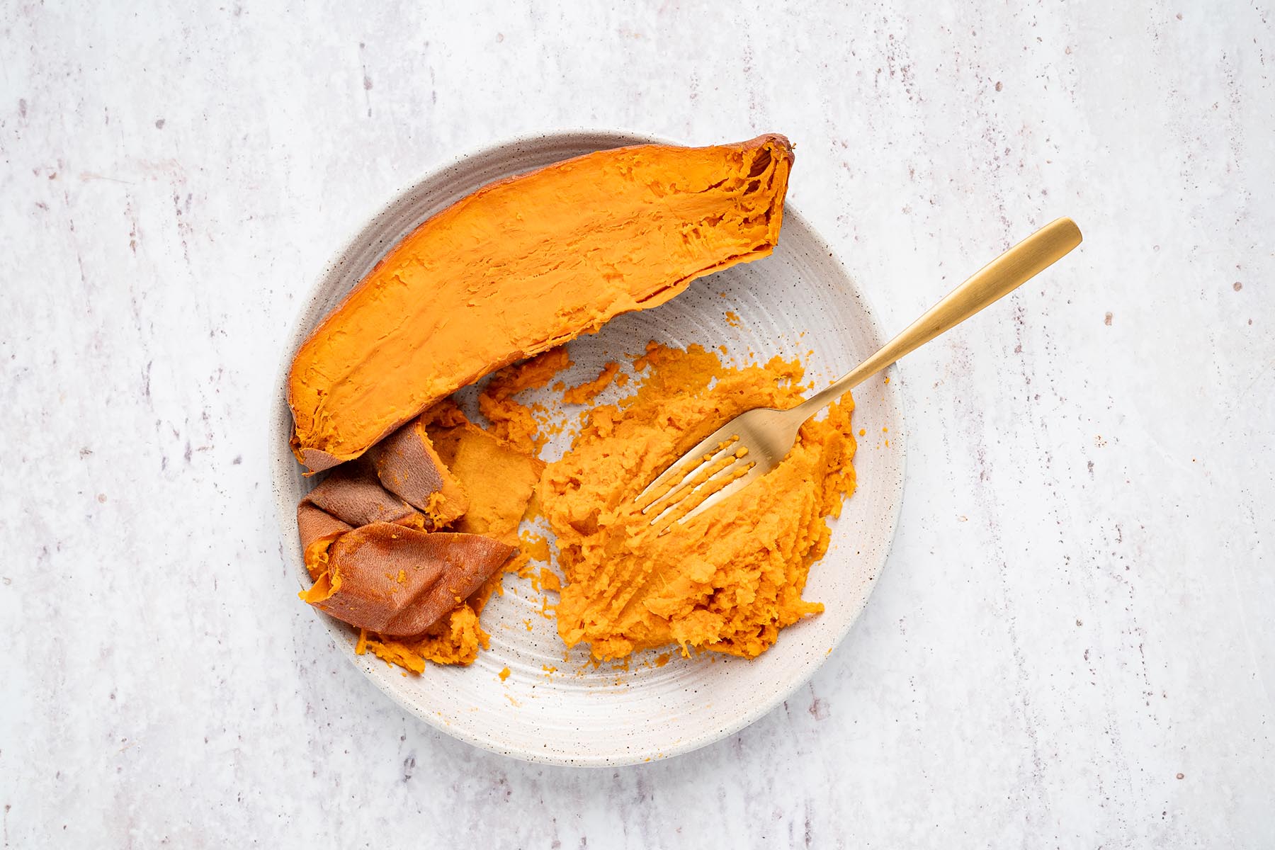 Cooked sweet potato with skin removed and flesh mashed smooth with a fork.